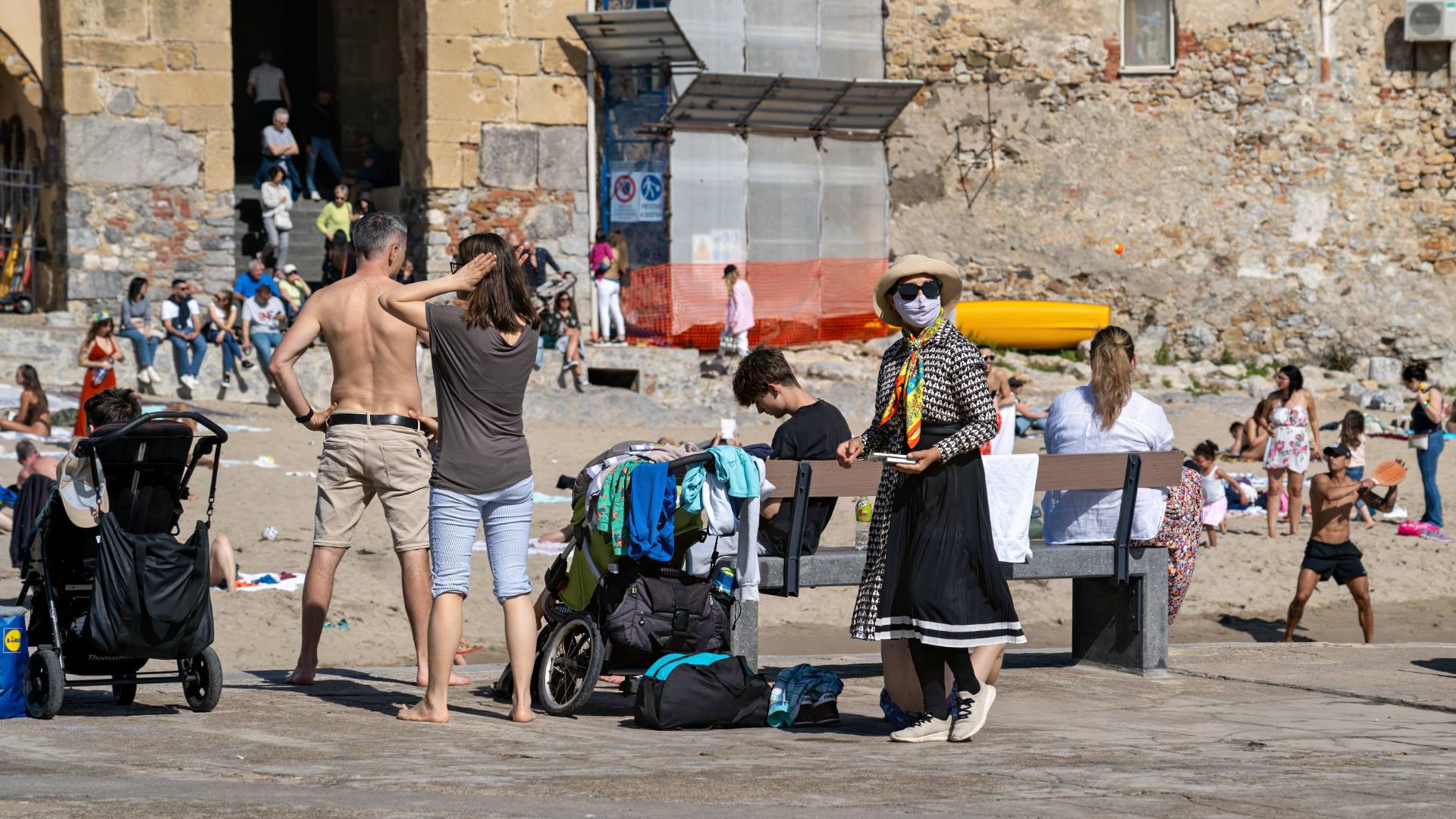 Stadtstrand - die sonnenscheue, tief verhüllte Japanerin wirkt am Strand etwas deplaziert